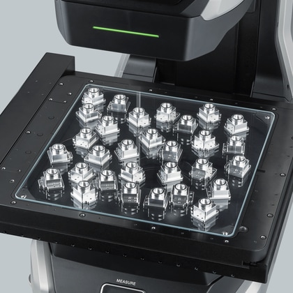 Around 30 identical machined metal blocks placed edge-to-edge across the full stage, with no trays or fixtures between them.