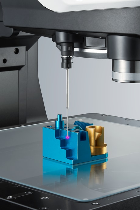 The touch probe tip descends to contact a single point on a workpiece held in a fixture on the measurement stage.