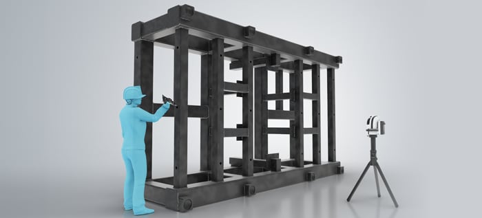 A worker measures a large frame structure alone on the shop floor.