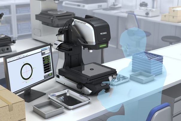 The measuring microscope set up on a bench in a prototyping lab, with the monitor showing a circular profile measurement in progress.