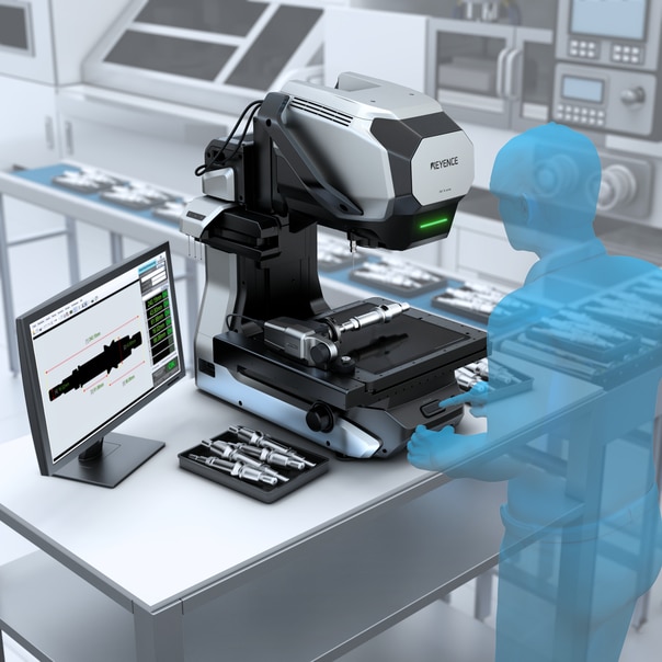 The measuring microscope on a production line, with a tray of needle-like parts beside it and the monitor showing a height profile graph.